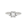 Thumbnail of Front view of the Hero Emerald Cut Three Stone Diamond Engagement Ring in 14k solid white gold, featuring a central 1ct emerald-cut diamond flanked by two smaller diamonds on a polished band.