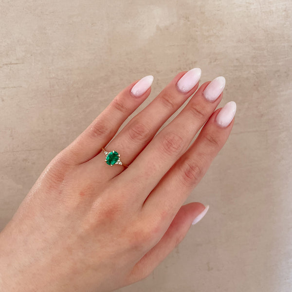 Alternative view of Close-up of a hand wearing the Dewlight Emerald Engagement Ring in 14k solid gold, on a polished band.