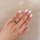 Close-up of a hand wearing the Dewlight Emerald Engagement Ring in 14k solid gold, on a polished band.