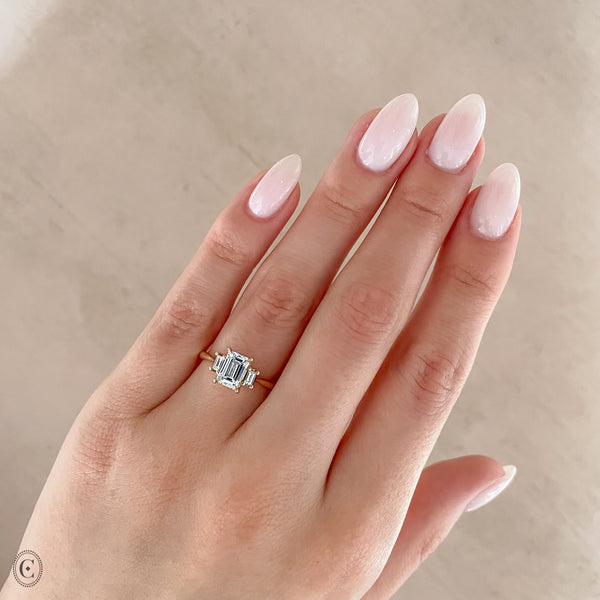 Alternative view of Close-up of a hand wearing the Hero Emerald Cut Three Stone Diamond Engagement Ring in 14k white gold.