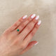 Close-up of a hand wearing the Love is All Emerald Engagement Ring in 14k white gold, on a polished band.