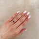 Close-up of a hand wearing the Love is All Blue Sapphire Engagement Ring in 14k solid gold, on a polished band.