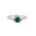 Front view of the Love is All Emerald Engagement Ring in 14k white gold, featuring a brilliant cut emerald on a polished band.