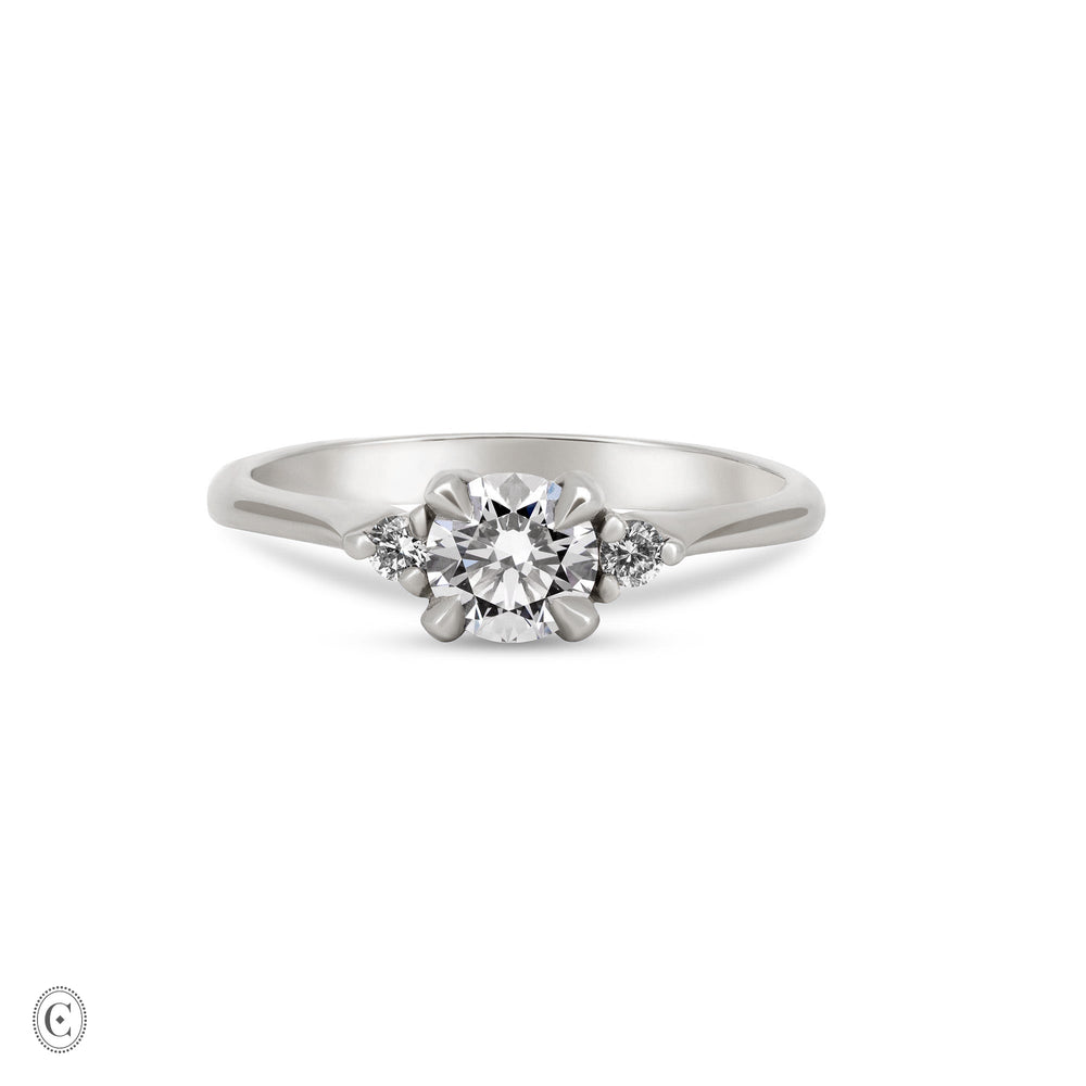 Front view of the You, Me & Magic Round Cut Three Stone Engagement Ring in 14k white gold, featuring a 0.5ct central round cut diamond flanked by two smaller stones on a polished band.